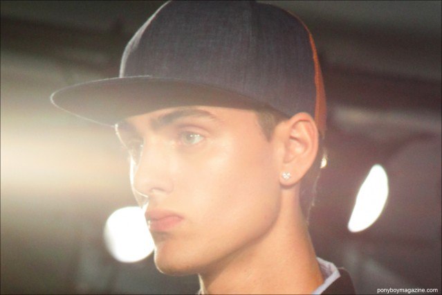 A male model in a baseball cap at the Rochambeau S/S15 presentation at Milk Studios in New York. Photographed by Alexander Thompson for Ponyboy Magazine.