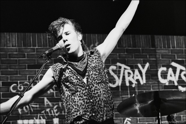 Slim Jim Phantom, drummer for rockabilly band Stray Cats, photographed singing onstage by Manfred Becker. Ponyboy magazine.