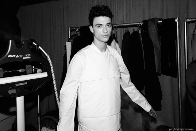 A male model photographed backstage in a white vest and shirt by Stampd F/W16 menswear label. Photography by Alexander Thompson for Ponyboy magazine.