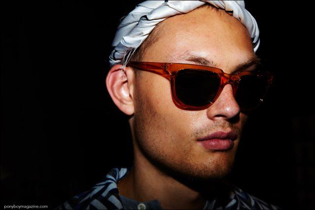 Close-up photo of a male model in headwear and sunglasses, backstage at Rochambeau Spring/Summer 2017 menswear show. Photography by Alexander Thompson for Ponyboy magazine.