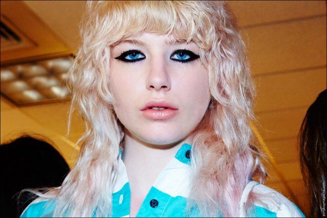 A blonde model photographed backstage during hair & makeup at Libertine Spring/Summer 2017. Photography by Alexander Thompson for Ponyboy magazine.