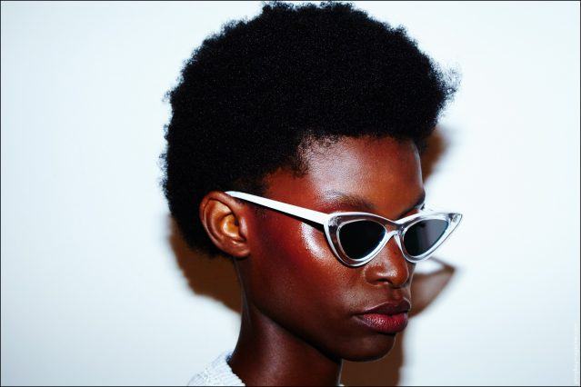 A model in afro and cat-eye glasses snapped backstage before walking for Adam Selman Spring/Summer 2017 show. Photography by Alexander Thompson for Ponyboy magazine.