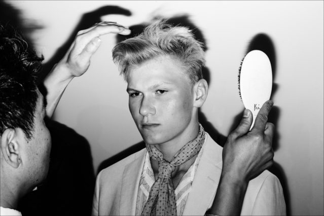 Hairstylist Kien Hoang for Oribe puts finishing touches on a male model, backstage at the David Hart Spring 2018 menswear show. Photography by Alexander Thompson for Ponyboy magazine.