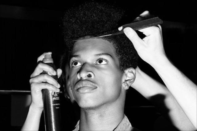 A model gets his hair prepped before walking backstage at Gustav Von Ashcenbach Spring 2018 menswear show by designer Robert Geller. Photographed by Alexander Thompson for Ponyboy magazine.