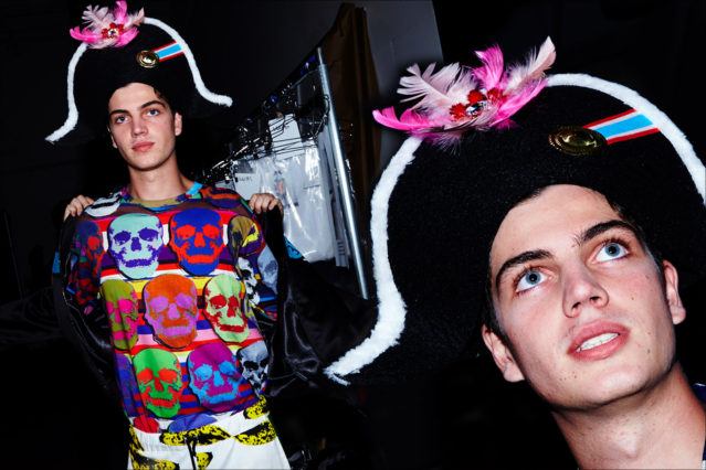 A male model wears a skull t-shirt and pirate hat backstage at Libertine for S/S18. Photography by Alexander Thompson for Ponyboy magazine.