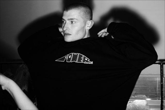 A model adjusts his hoodie at the Willy Chavarria menswear show for Fall 2018. Photography by Alexander Thompson for Ponyboy magazine.