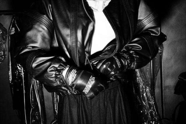 A model adjusts his leather jacket backstage at the Willy Chavarria menswear show for Fall 2018. Photography by Alexander Thompson for Ponyboy magazine.